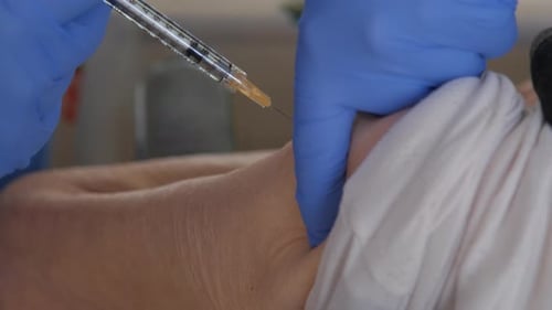 Close-up of an elderly patient's arm as they receive the COVID-19 vaccine.