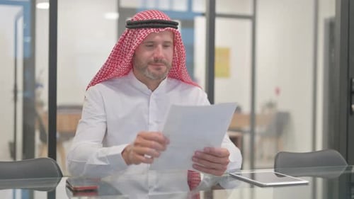 Bearded Man Reviews Documents at Office Conference Table