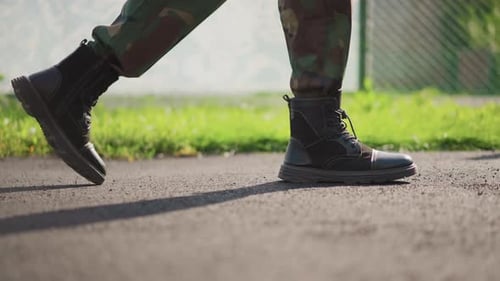 Black Boots Walking on Asphalt in Urban Setting
