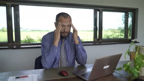 Bearded Man with Headache Working at Desk