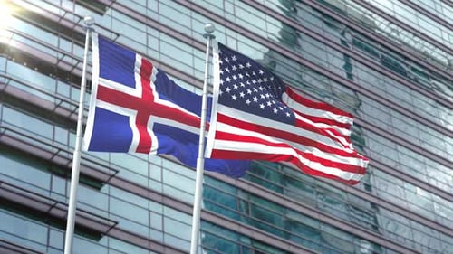 Iceland and USA Flags Waving in Wind Against Modern Building