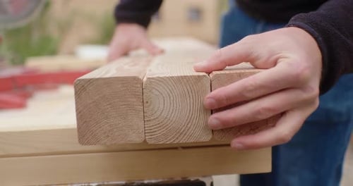 Hands Aligning Cut Pieces of Wood
