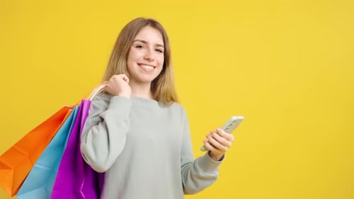 Smiling Woman with Shopping Bags Using Phone