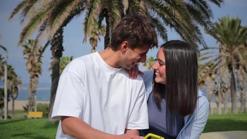Happy Couple Laughing at Phone on Tropical Beach