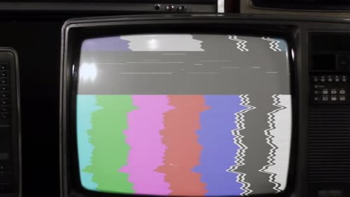 Retro TV With Color Bars Flicker Turning On, Then Green Screen, Surrounded by Old Televisions