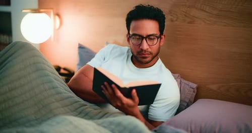 Man Reading Book in Bed at Night