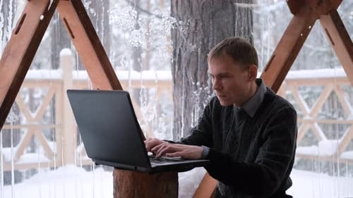 Adult Typing on Laptop in Snowy Gazebo