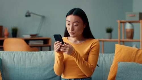 Woman Using Phone, Relaxing on Sofa at Home