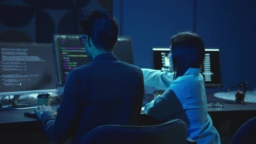 Zwei Softwareentwickler programmieren auf Computern im Dark Office