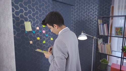 Office worker takes notes and sits at his desk.