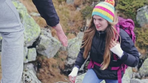 Woman Climbing Rocky Hill with Assistance from Man