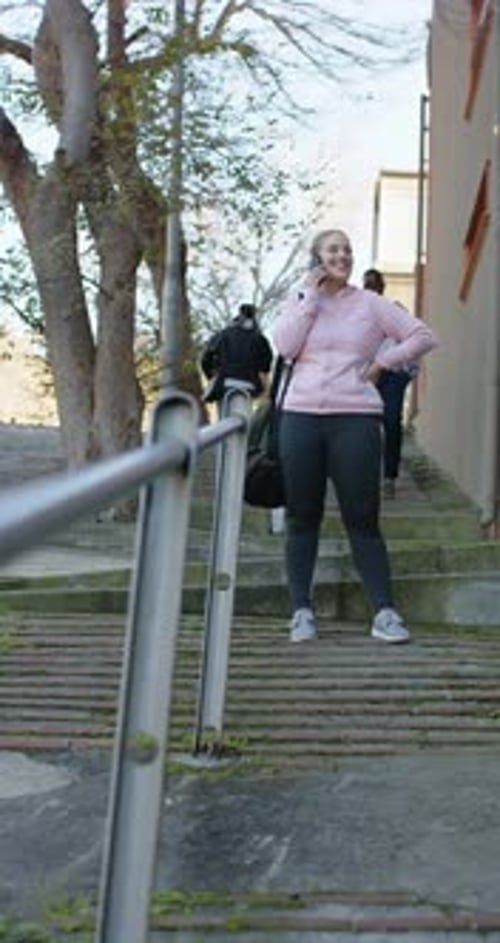 Vidéo verticale : smartphone qui sonne, femme qui monte les marches, répond à un appel et ajuste la sangle du sac