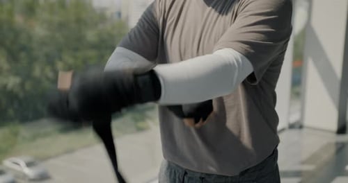 Closeup of Male MMA Fighter Wrapping Hands Preparing for Fight and Training in Light Gym