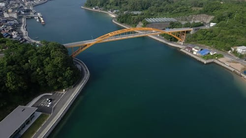 Slow cinematic drone tilt up over yellow bridge at Kikuchi Island in Japan