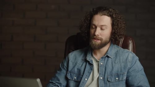 Man Talking at Desk with Laptop