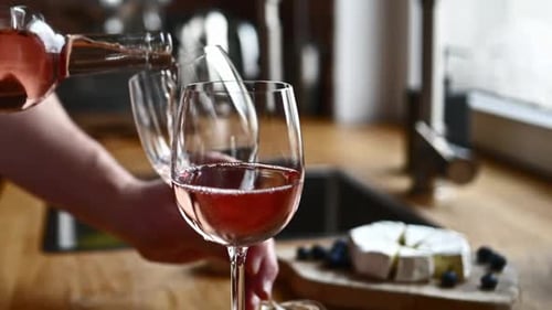 Hombre con botella de vino y vasos en la cocina