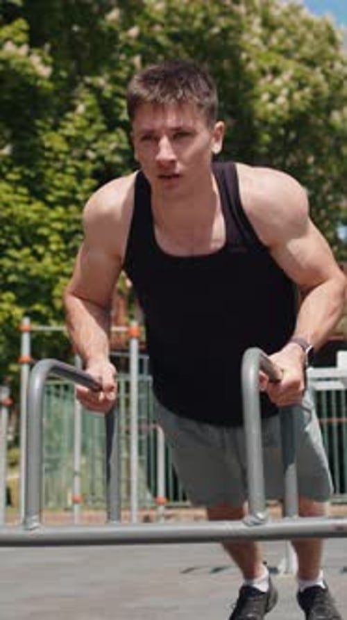 Muscular Man Working Out on Parallel Bars Outdoors
