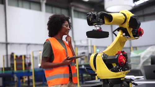 Female engineer in factory with robotic arm, blending human expertise and automation in modern manuf
