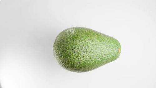 Green Ripe Avocado Rotates on a White Background, Looping. Top View, Isolated.
