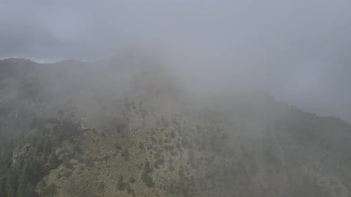 Moving to left above mountain in a foggy day with view of Pico del Aguila in Mexico City