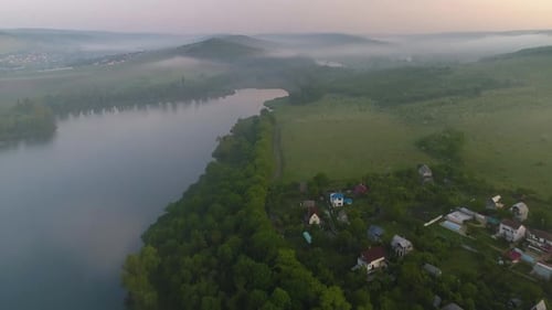 vue aérienne d'un petit village au bord d'un lac avec brouillard et forêt en arrière-plan