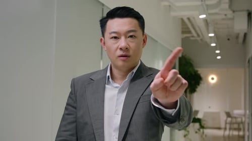 Man Stands in Office Hallway Raising Finger