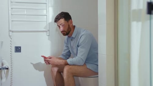 Happy Businessman Use Phone Sitting on the Toilet Smiling Mobile Restroom Smartphone Internet Home
