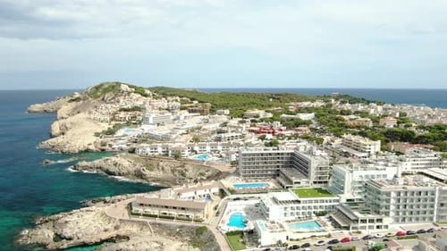 Aerial panning view of a beautiful sea and beach with resorts and natural parks around.