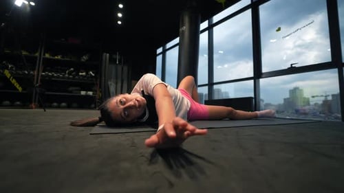 Young Woman Performs Exercise Exercising Lying on Mat in Gym