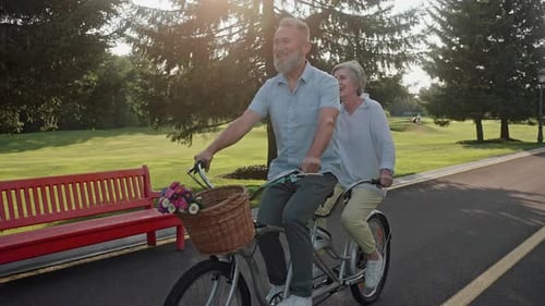 Active Grandparents Cycling on Tandem Bike on Street