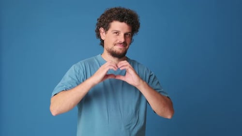 Smiling Man Makes Heart Shape with Hands