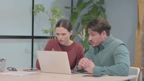 Woman and Man Collaborating on Laptop in Office