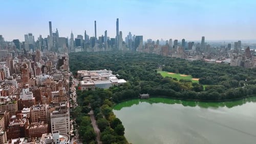 Lovely green area of Central Park in New York neighboring with dense city architecture.