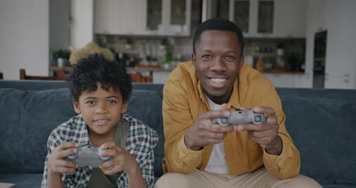Smiling Man and Child Playing Video Games