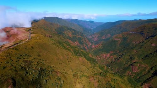 Flight above the rocky landscape covered with green mosses. White clouds roll on the mountain tops