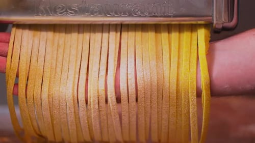 Italian Pasta Being Made on the Machine for Cutting Dough Fresh Handmade Pasta Coming Out From