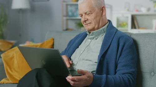 Senior Man Using Laptop on Couch at Home
