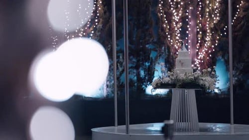 Elegant wedding cake with floral base under string lights at night