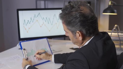 Reifer Geschäftsmann, der Einkommensdiagramme und Grafiken mit einem modernen Computer analysiert.