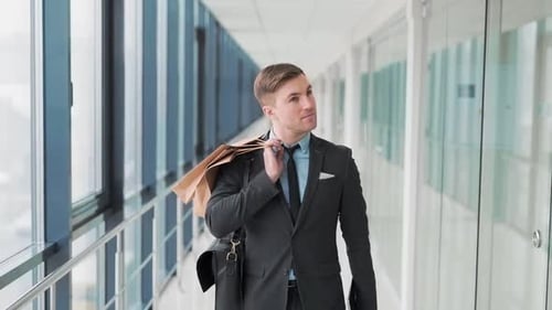 Pretty smiling man walks down the hall of shopping mall after shopping