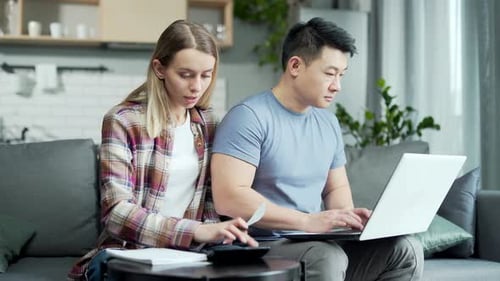 Couple Uses Laptop on Couch Indoors