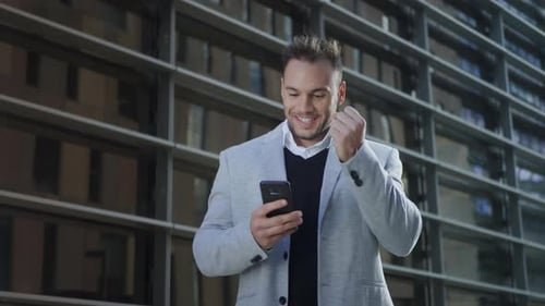 Happy Businessman Reading Good News on Smartphone at Street. Portrait of Smiling