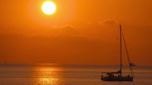 Sailboat Silhouetted Against Golden Sunset Over Ocean