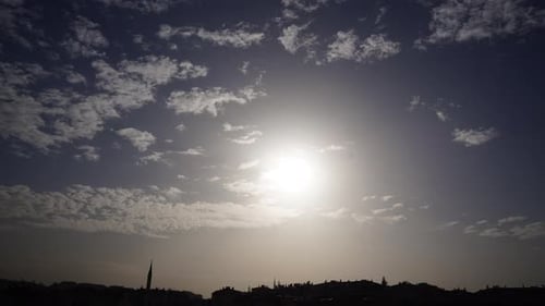 Timelapse of clouds and sunlight passing over mosque and cityscape