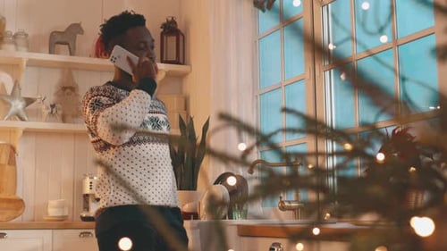 Young Man Talking on Phone in Christmas Kitchen