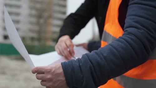 Construction engineers at the construction site are discussing the project of a high-rise building.