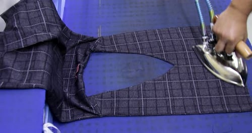 Tailor ironing clothes in tailoring shop