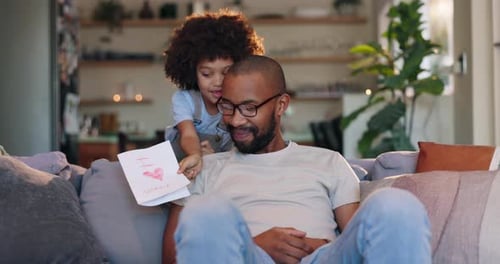 Daughter Giving Handmade Card to Dad on Couch