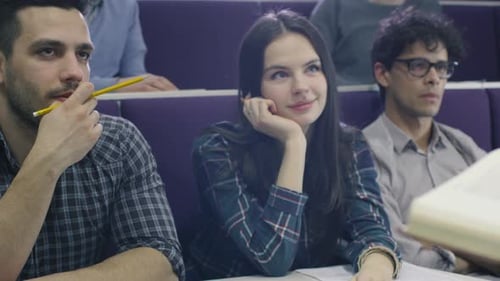 College professor is teaching a class of multi-ethnic students while holding a book.