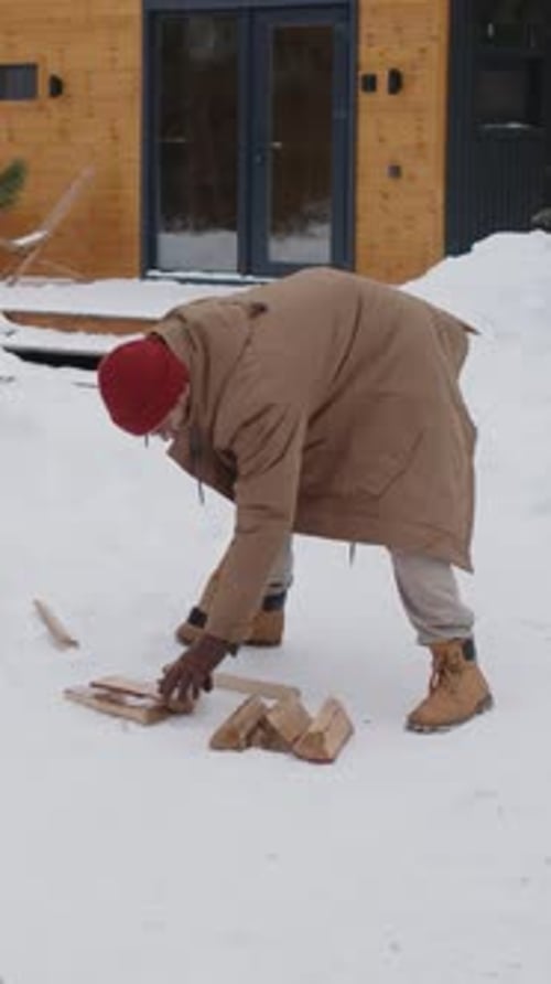 Vertical of Man Splitting Woods on Snowy Front Yard